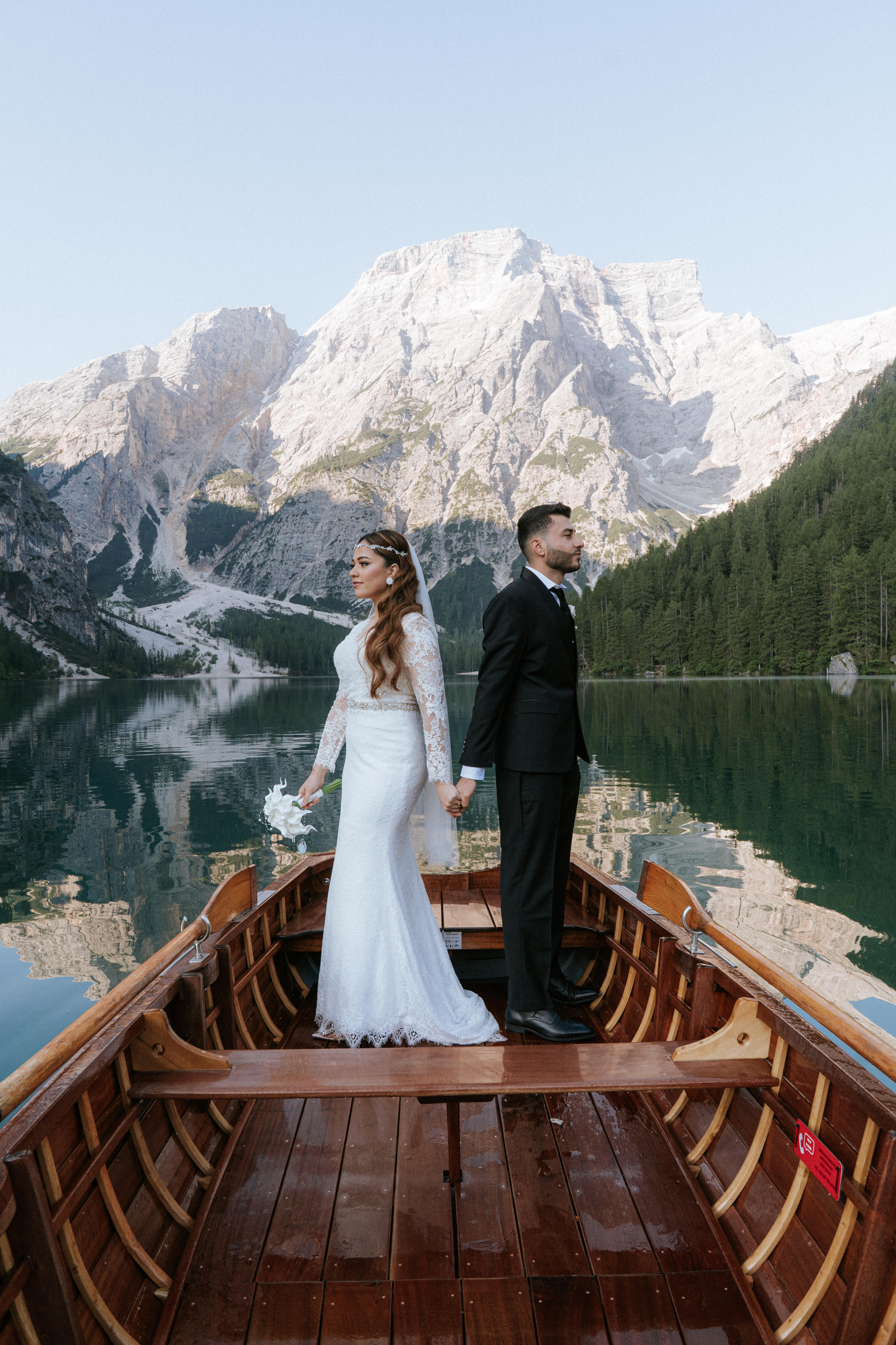 Bride with flowing wedding dress at Lago di Braies with the lake and Dolomites reflected in the calm water